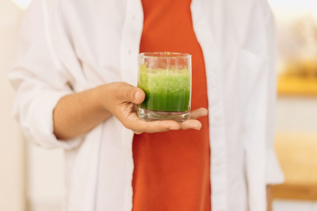Close-up of a person holding a refreshing green smoothie, symbolizing a healthy lifestyle.