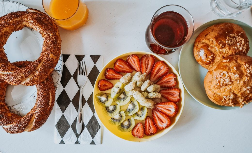 Colorful breakfast with fruit platter, pastries, and drinks on table. A vibrant start to the day.