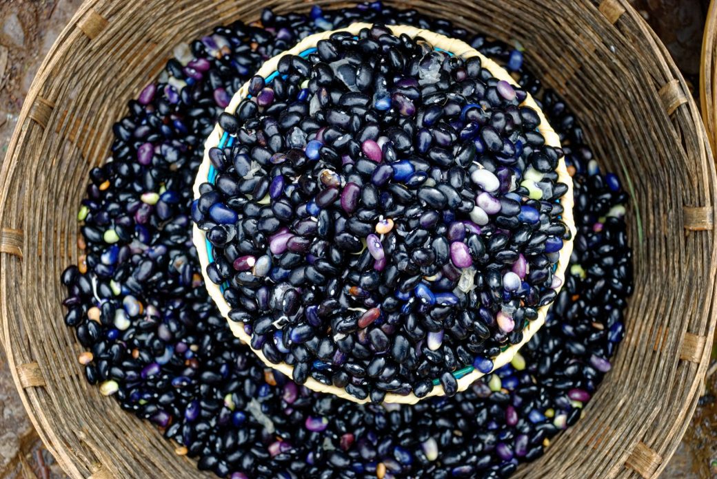 A collection of raw black beans in a woven basket, perfect for culinary and agricultural themes.
