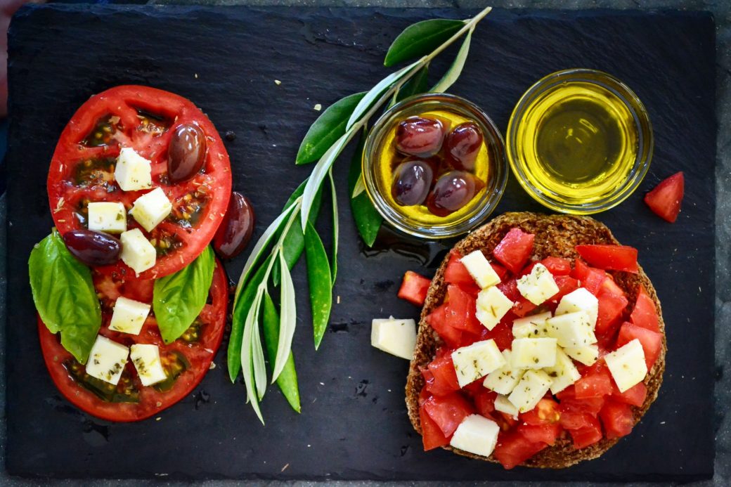 A vibrant Greek salad featuring tomatoes, feta, and olives on a slate board, perfect for healthy eating.