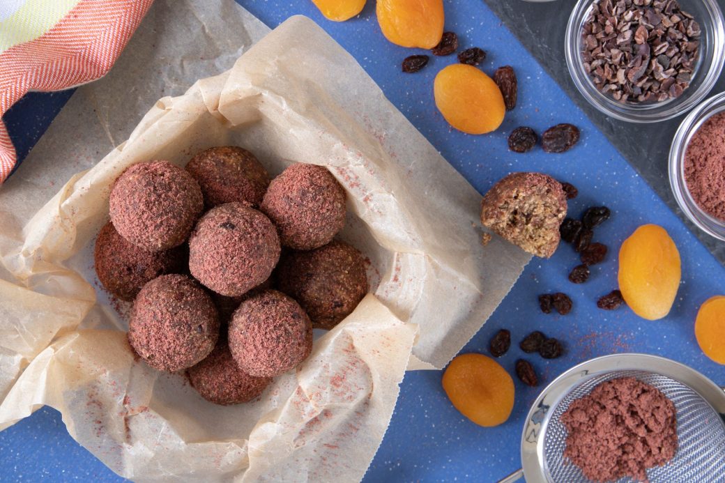 Homemade energy balls with cocoa and dried fruits on parchment paper.