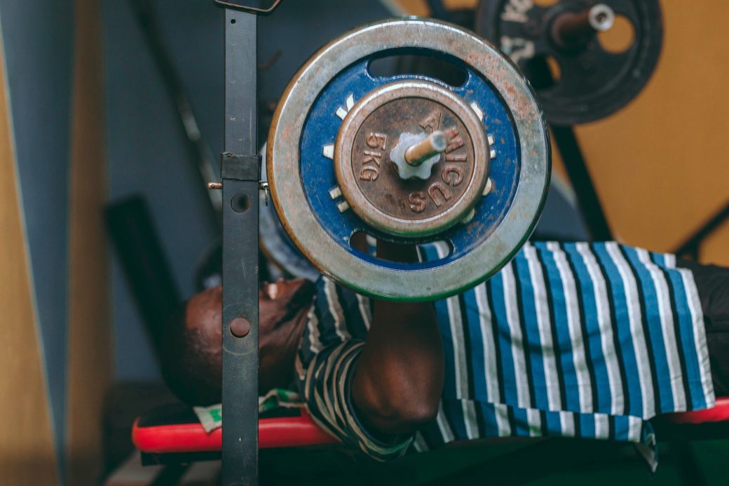 A man lifting weights with a barbell in an indoor gym setting, focused on fitness and strength training.